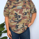 Person wearing a camouflage t-shirt with 'Billa Bong' logo against a white background