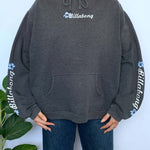 Person wearing a grey hoodie with Billabong spellout and flower logo on a white background