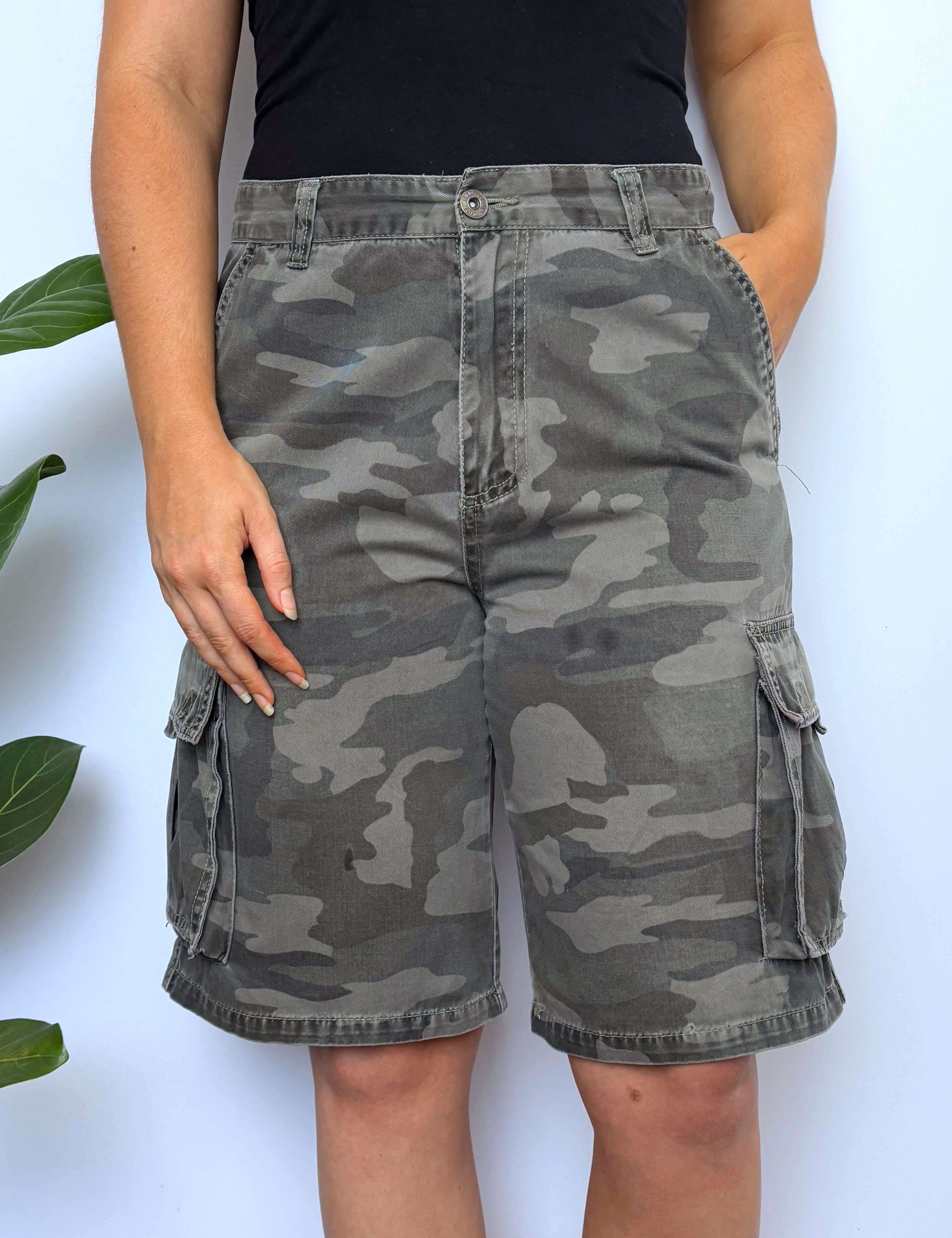 Person wearing camouflage shorts with a plain background